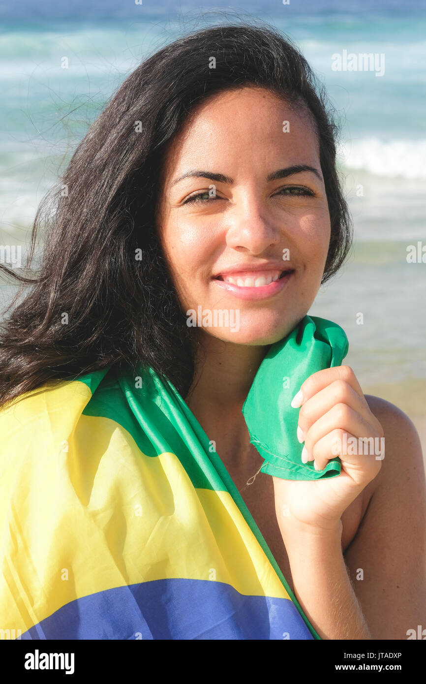 Junge Brasilianerin, 20 bis 29 Jahre alt, in die brasilianische Flagge auf einem Strand in Rio de Janeiro, Brasilien gewickelt Stockfoto