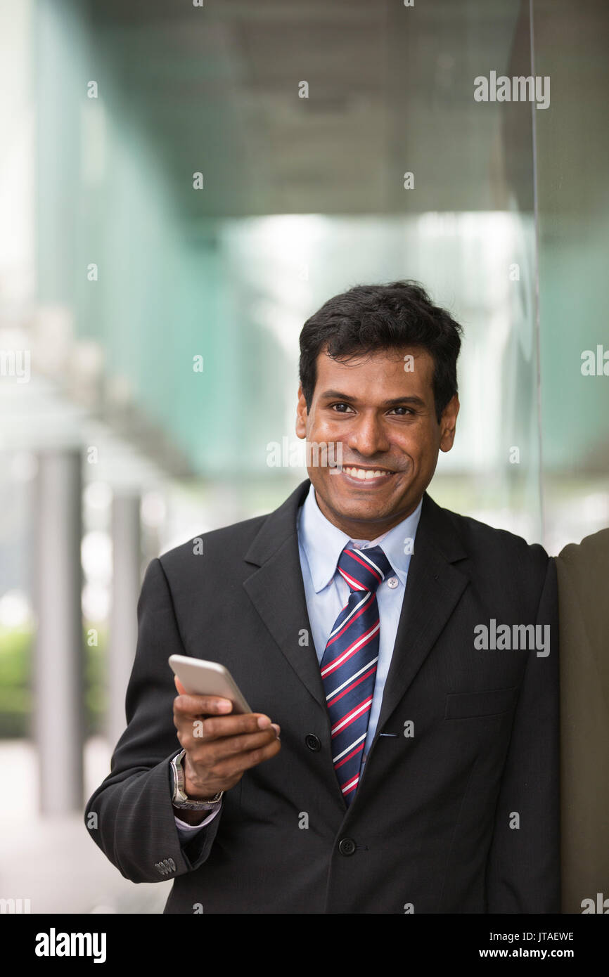 Indische Geschäftsmann mit seinem Smart Phone im Freien in einer asiatischen Stadt. Stockfoto