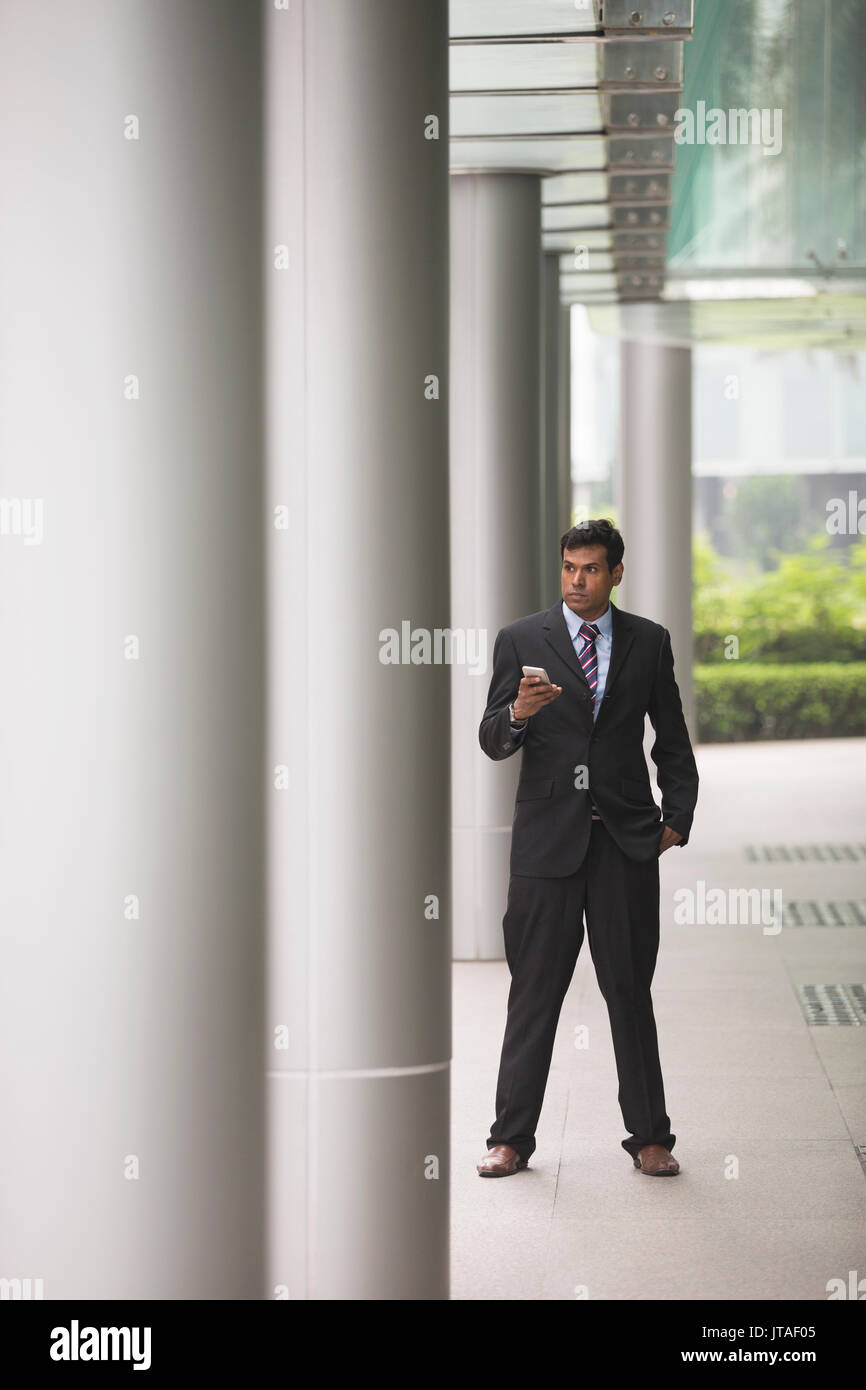 Indische Geschäftsmann mit seinem Smart Phone im Freien in einer asiatischen Stadt. Stockfoto