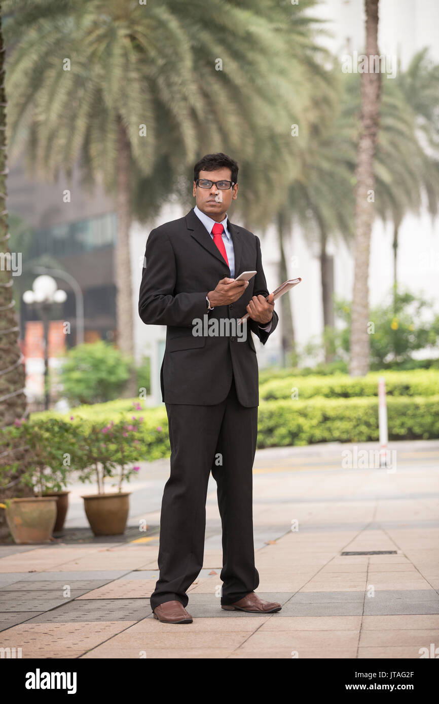 Indische Geschäftsmann mit seinem Smart Phone im Freien in einer asiatischen Stadt. Stockfoto