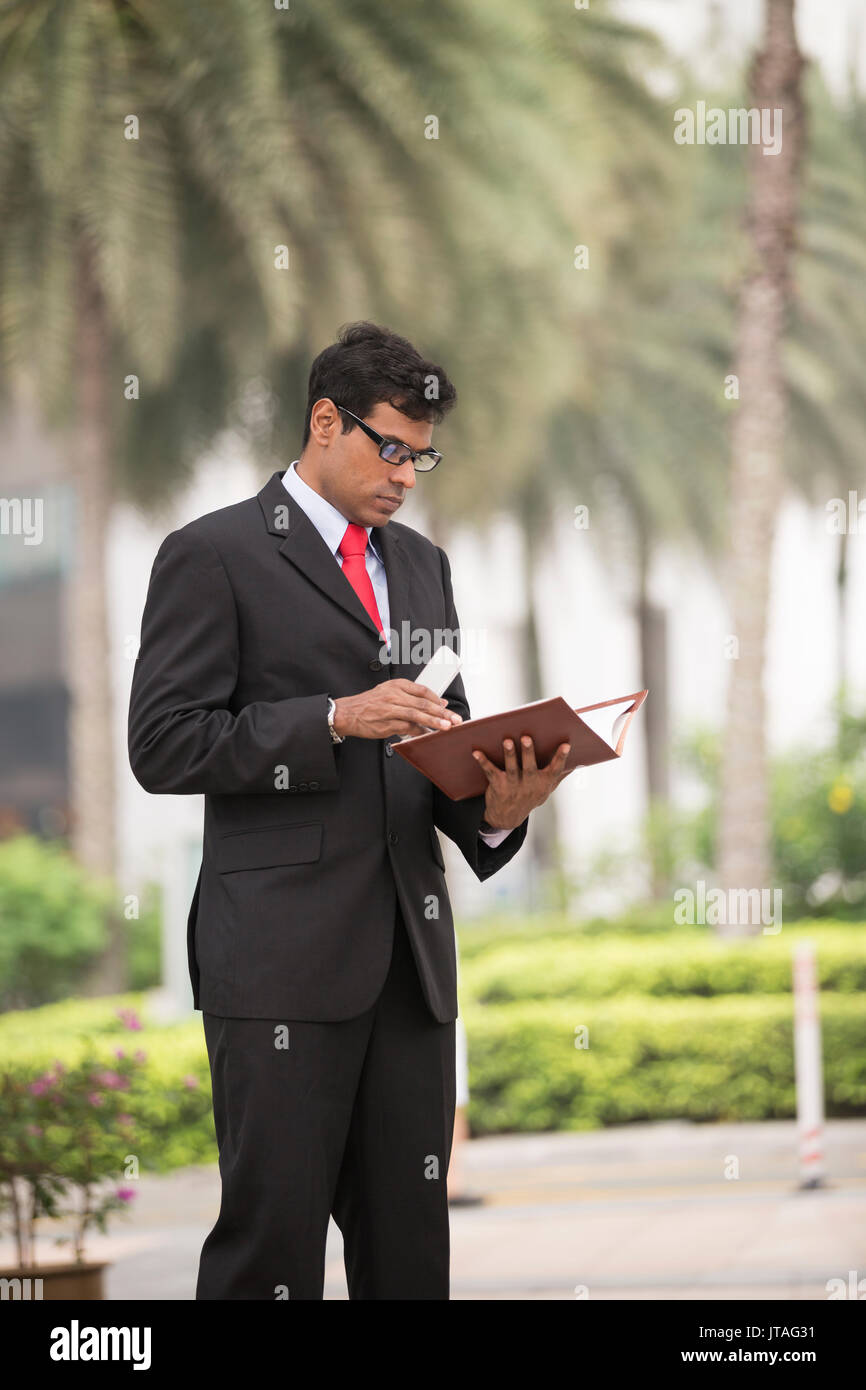 Indische Geschäftsmann mit seinem Smart Phone im Freien in einer asiatischen Stadt. Stockfoto