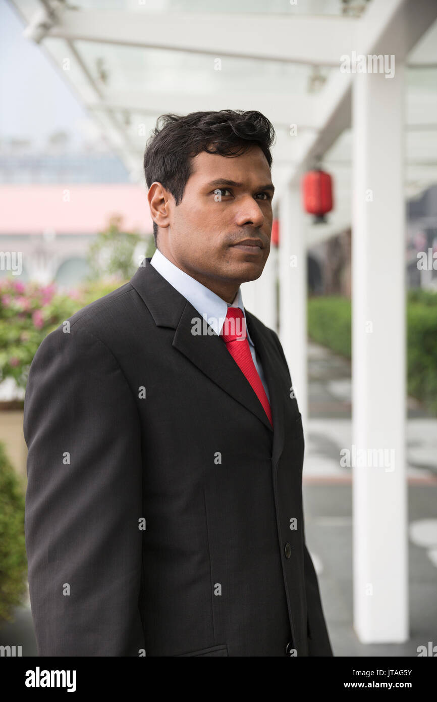 Indische Geschäftsmann in einer asiatischen Stadt. Porträt eines asiatischen Geschäftsmann lächelnd und weg von der Kamera. Stockfoto