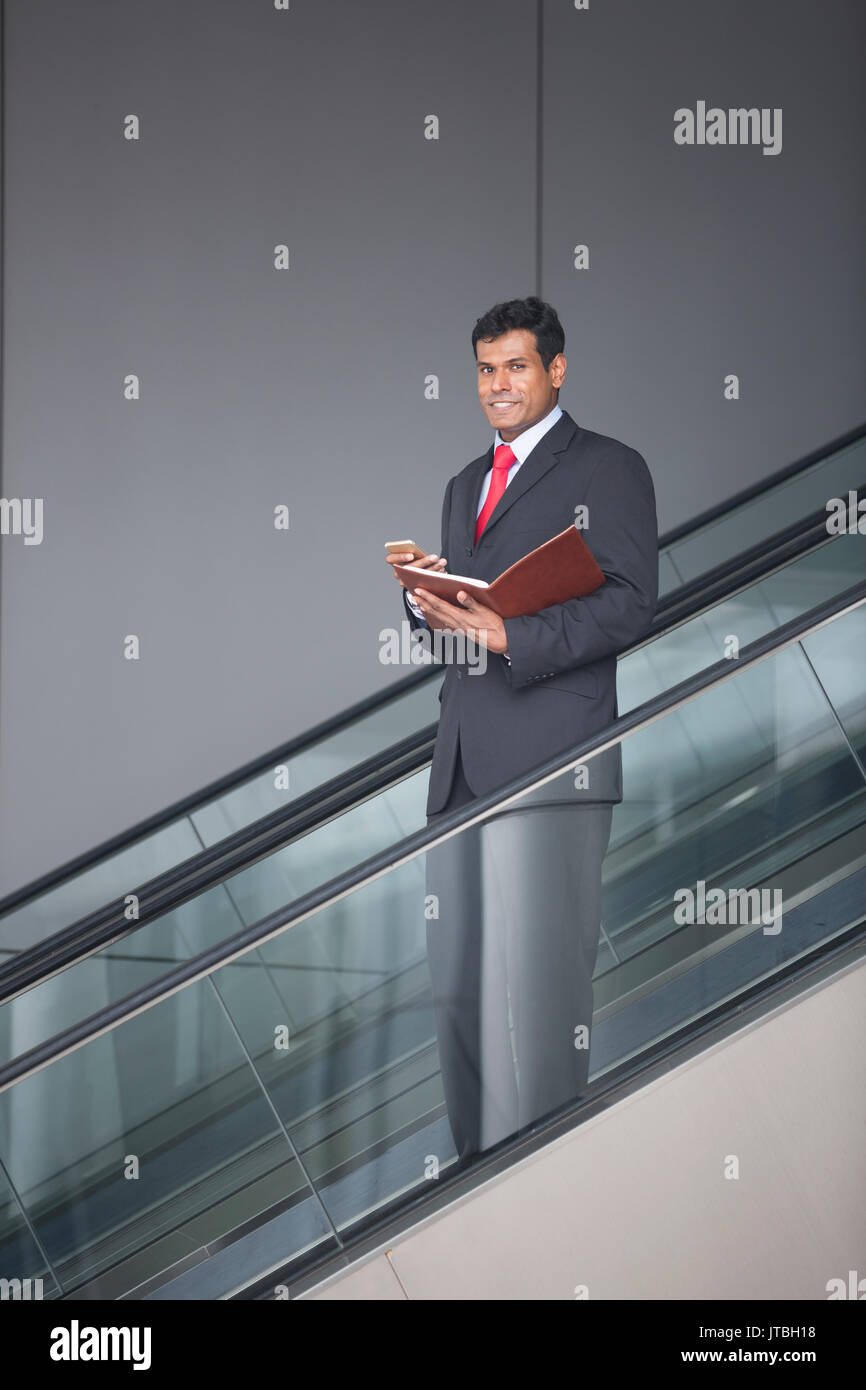 Porträt einer zuversichtlich indischer Geschäftsmann stehend auf einer Rolltreppe in der Stadt. Stockfoto