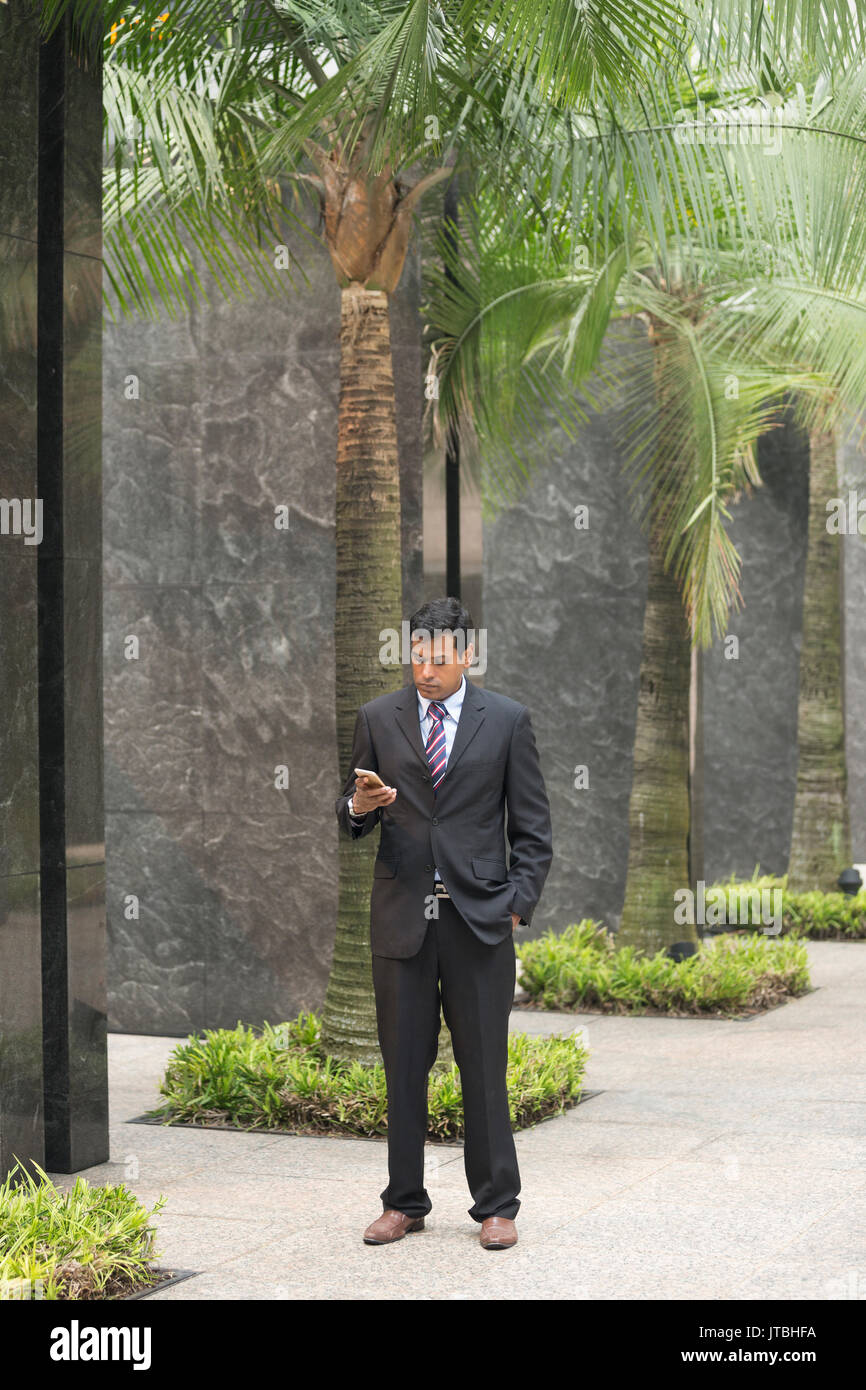 Indische Geschäftsmann mit seinem Smart Phone im Freien in einer asiatischen Stadt. Stockfoto