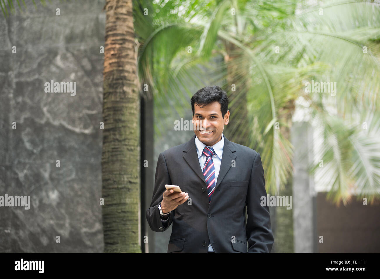 Indische Geschäftsmann mit seinem Smart Phone im Freien in einer asiatischen Stadt. Stockfoto