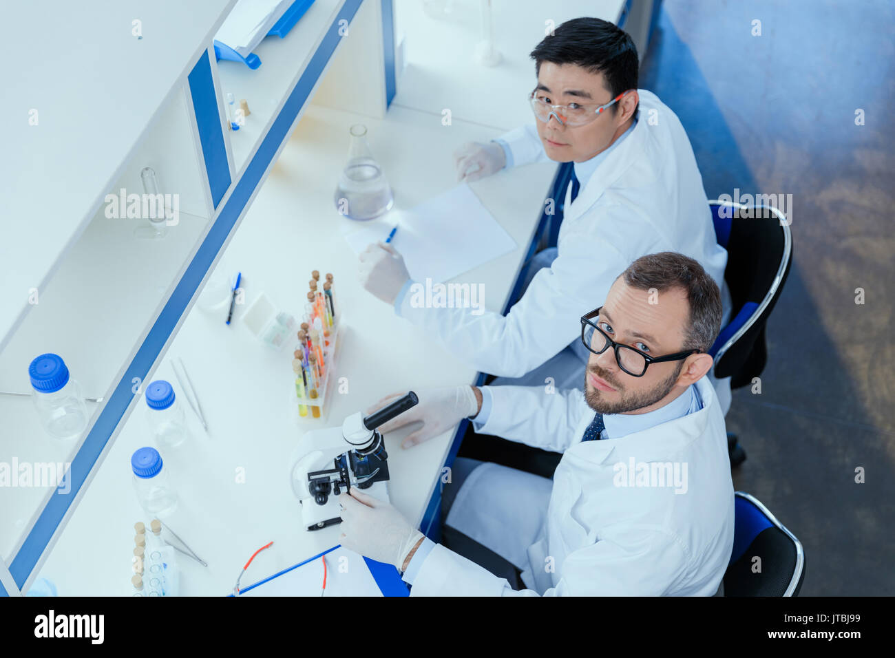Hohe Betrachtungswinkel der Chemiker in Brillen und Labormäntel zusammen im chemischen Labor Stockfoto