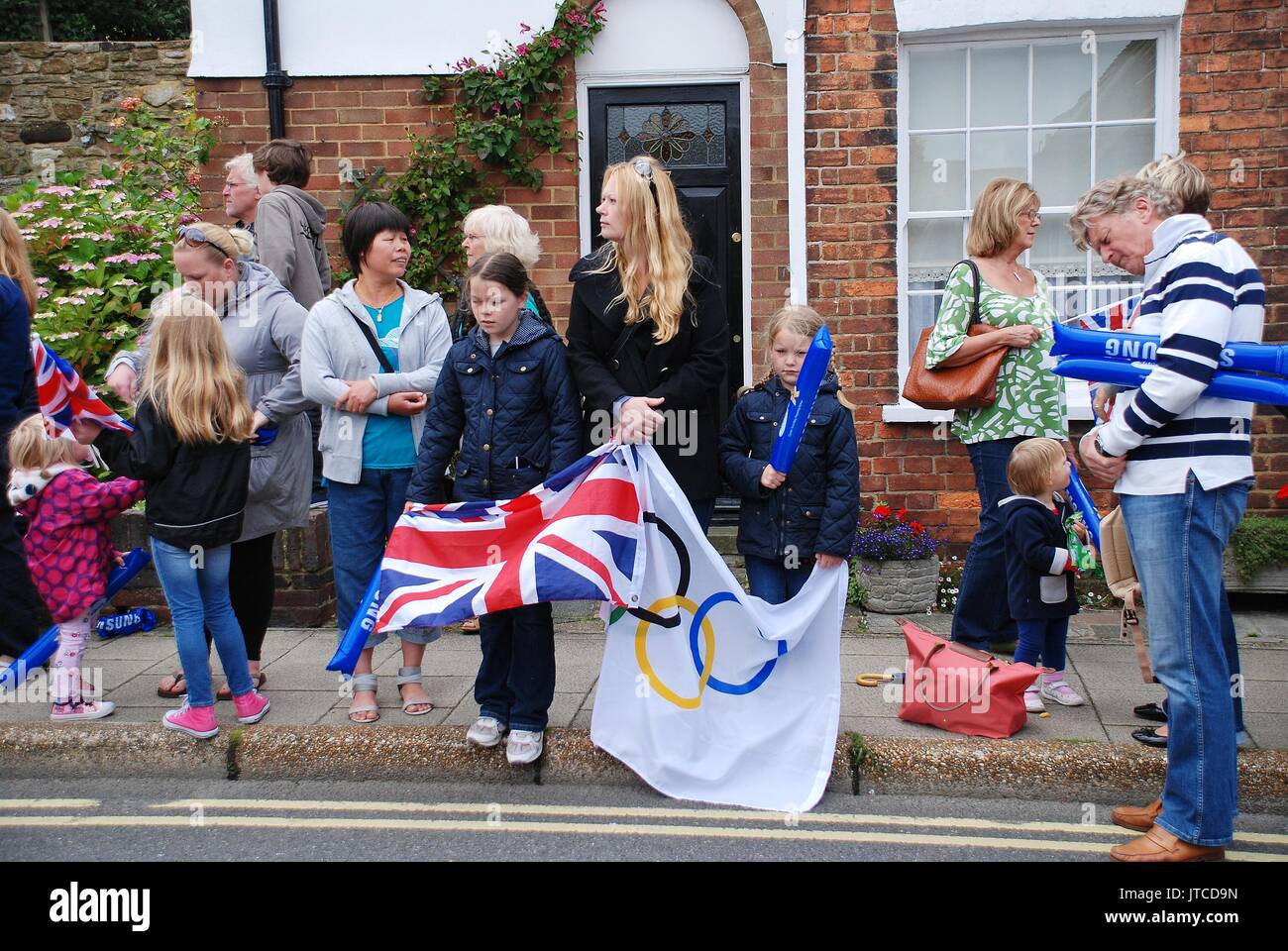 Die Menschen warten auf der Straße vor einem Olympischen Fackellauf Veranstaltung in Rye in East Sussex, England am 18. Juli 2012. Stockfoto