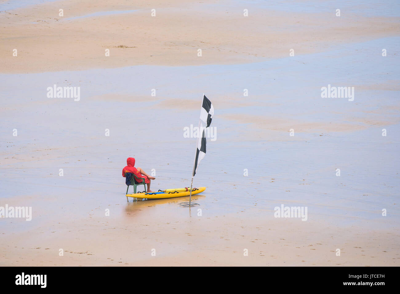Ein einsamer RNLI Rettungsschwimmer an einem ruhigen Strand in Newquay, Cornwall. Stockfoto