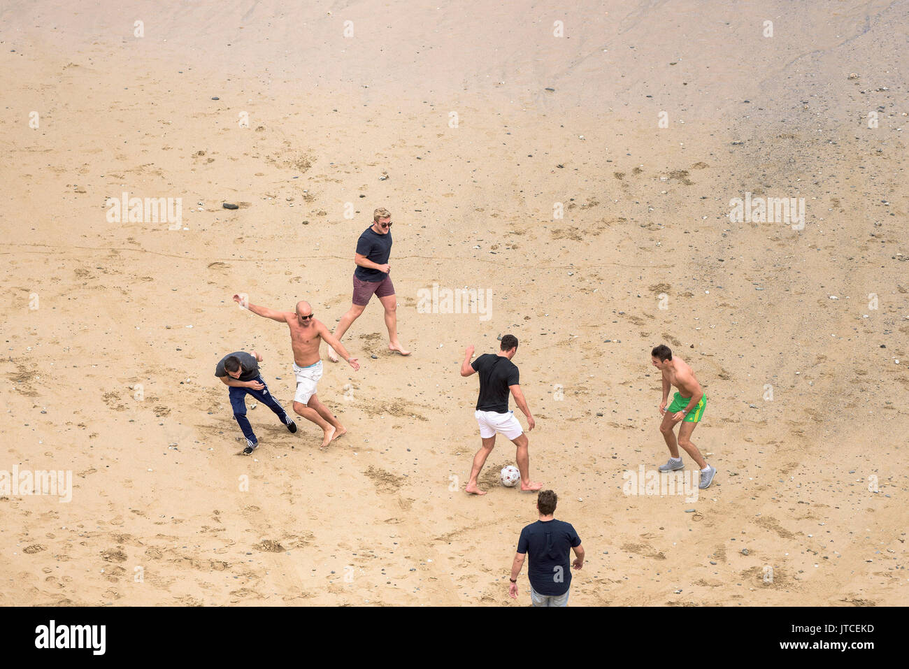Eine Gruppe junger Männer Fußball spielen auf einem Strand in Newquay, Cornwall. Stockfoto