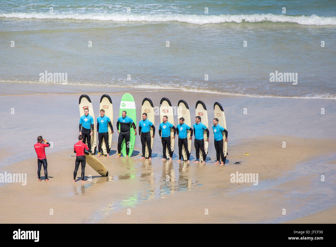 Eine Gruppe von Surf School Studenten für ein Foto vom Great Western Beach in Newquay, Cornwall posieren. Stockfoto