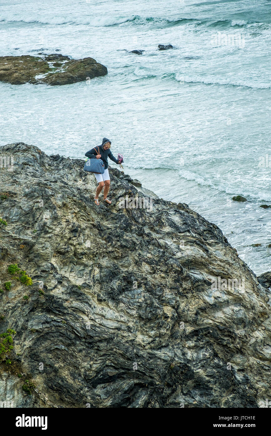 Eine Frau Abstieg rutschigen Felsen auf godrevy Beach, Cornwall. Stockfoto