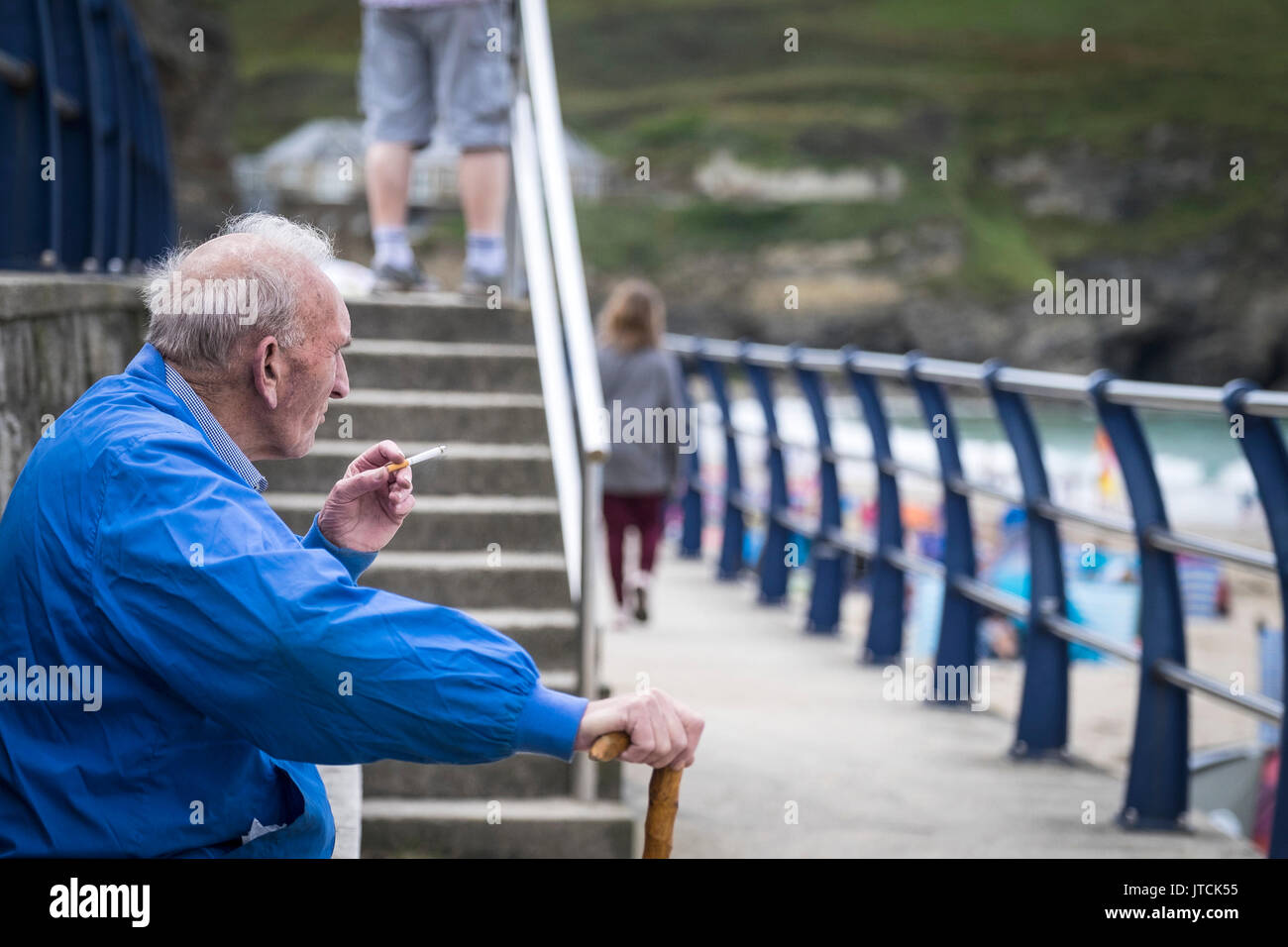 Eine ältere Urlauber das Rauchen einer Zigarette und entspannen im Portreath in Cornwall. Stockfoto