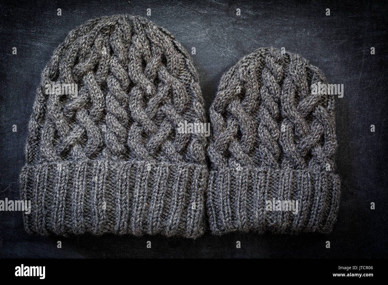 Zwei Größen von Hand stricken wolle Hüte mit Kabel. Für ein Kind, die anderen für einen Erwachsenen. Stockfoto