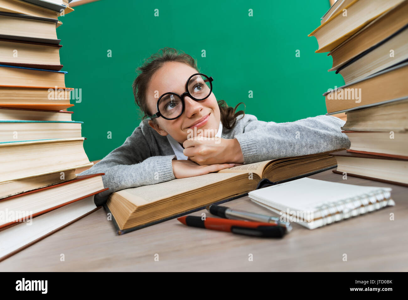 Schüler träumen oder denken an etwas Angenehmes während am Schreibtisch mit offenem Buch sitzen. Bildung Konzept Stockfoto
