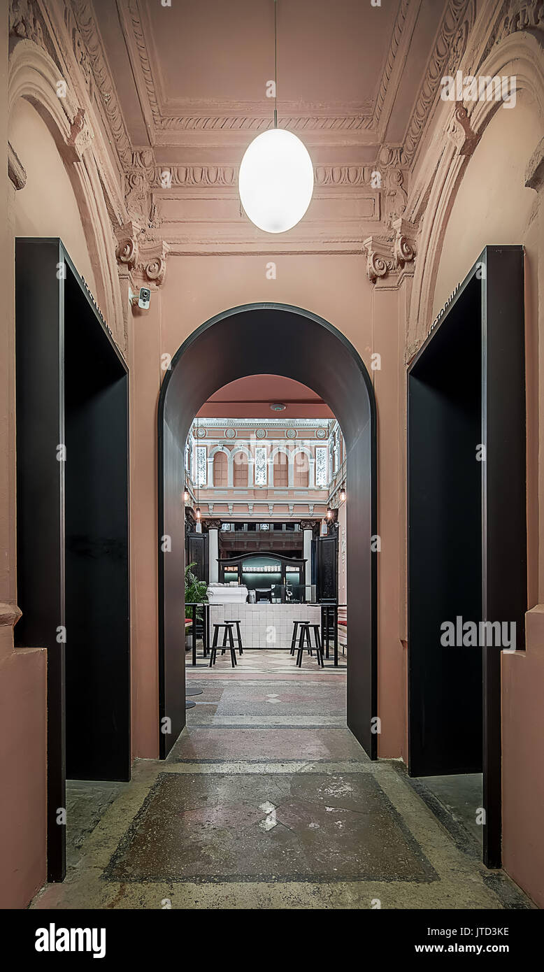 Arch schwarz Eingang zur Halle in ein Restaurant mit Wände mit Stuckverzierungen. Es ist ein Fliesen- Rack, Sideboard, Tisch mit Stühlen, strukturiert Stockfoto