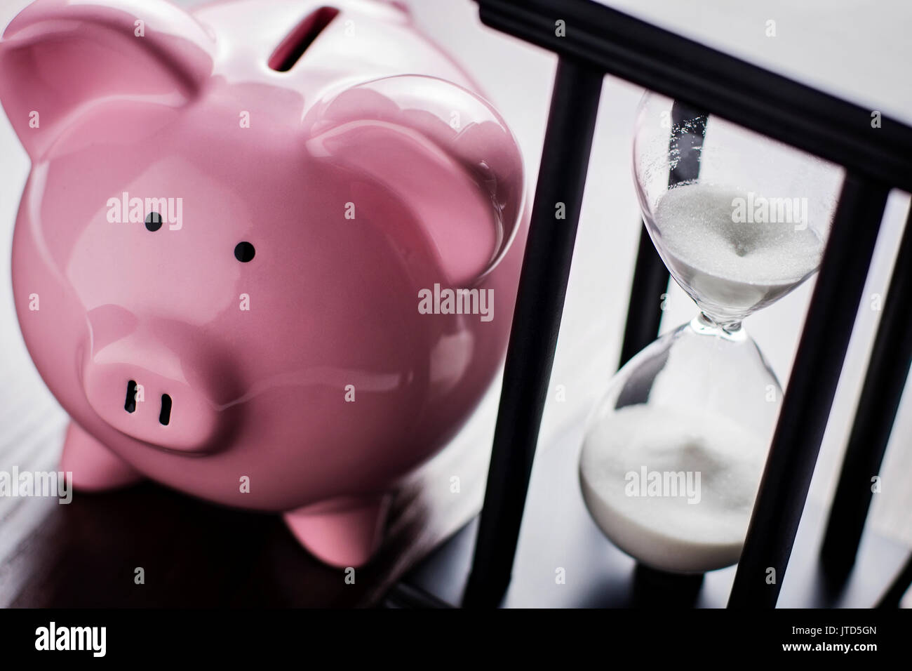 Rosa Keramik Sparschwein mit einer Stunde Glas, konzeptionelle läuft die Zeit für den Ruhestand zu sparen, ein Nest ein Ei oder ihre Träume zu erfüllen Stockfoto
