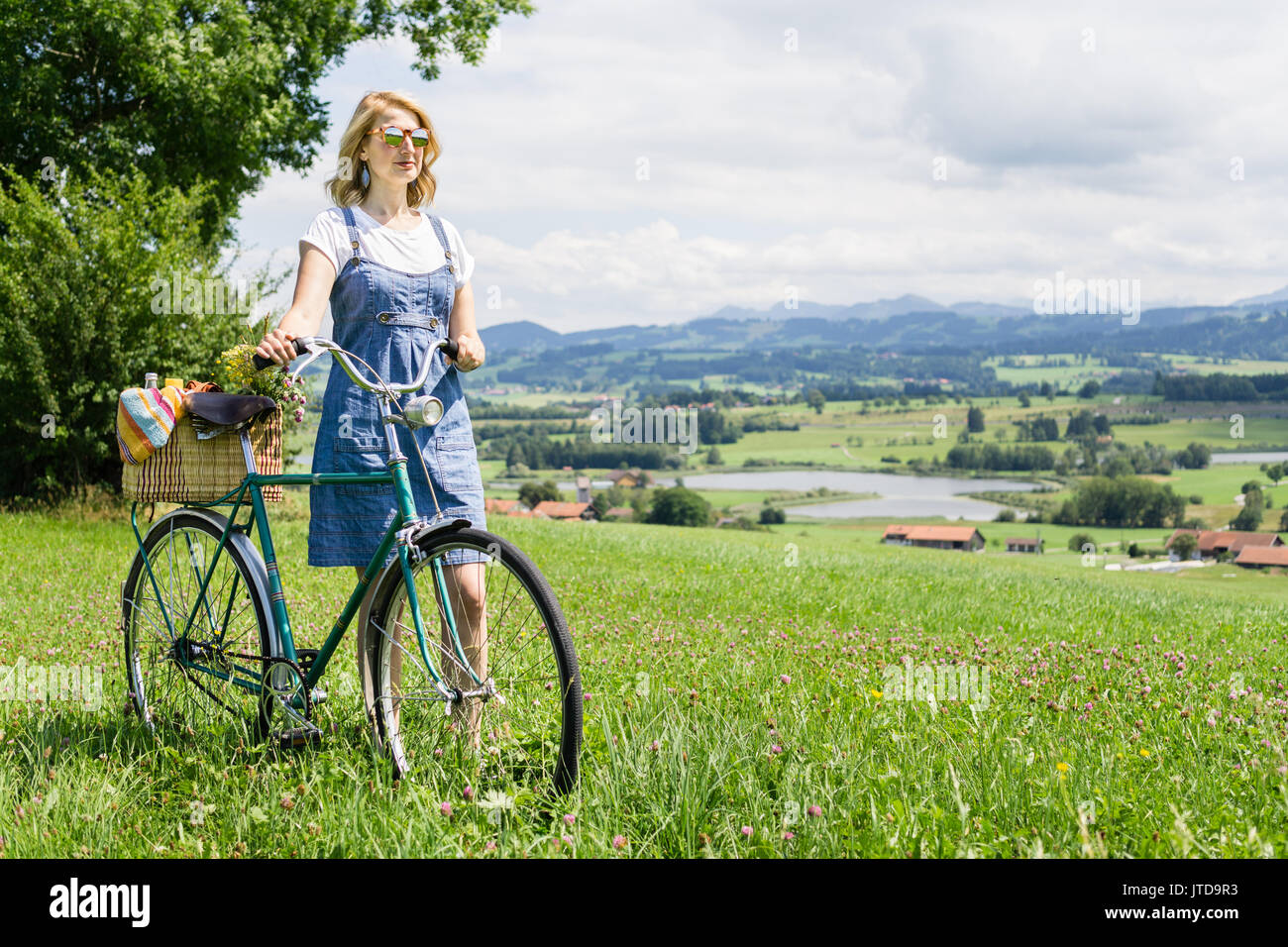 Frau gehen mit retro Fahrrad- und Korb auf Blumenwiese Stockfoto