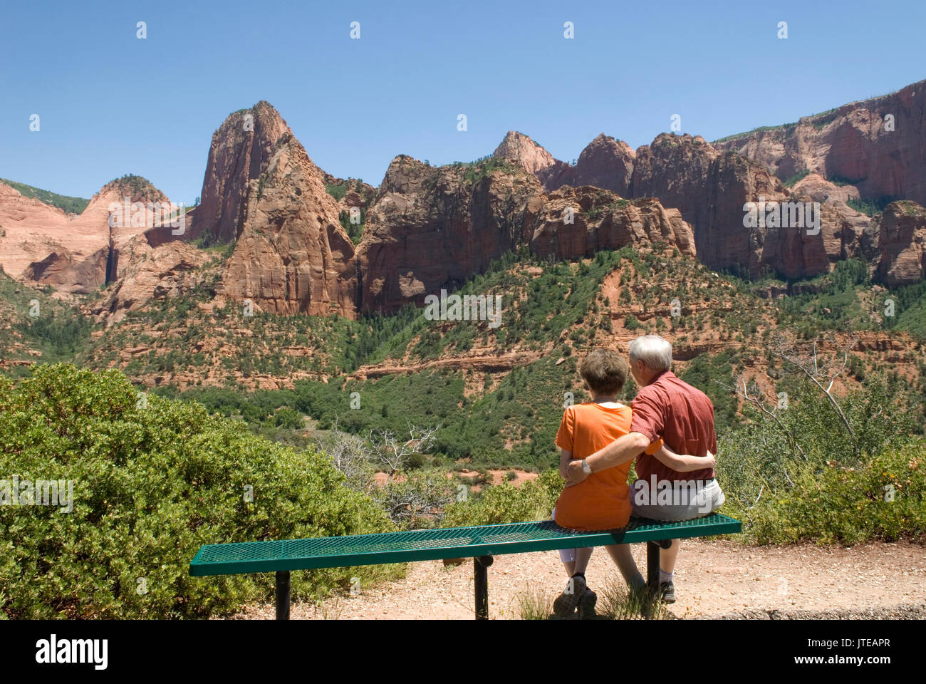 Kaukasisches Seniorenpaar (60-70 Jahre), das auf einer Bank mit umeinander verarmten Armen in Kolob Canyons im Zion National Park Springdale Utah, USA, sitzt. Stockfoto