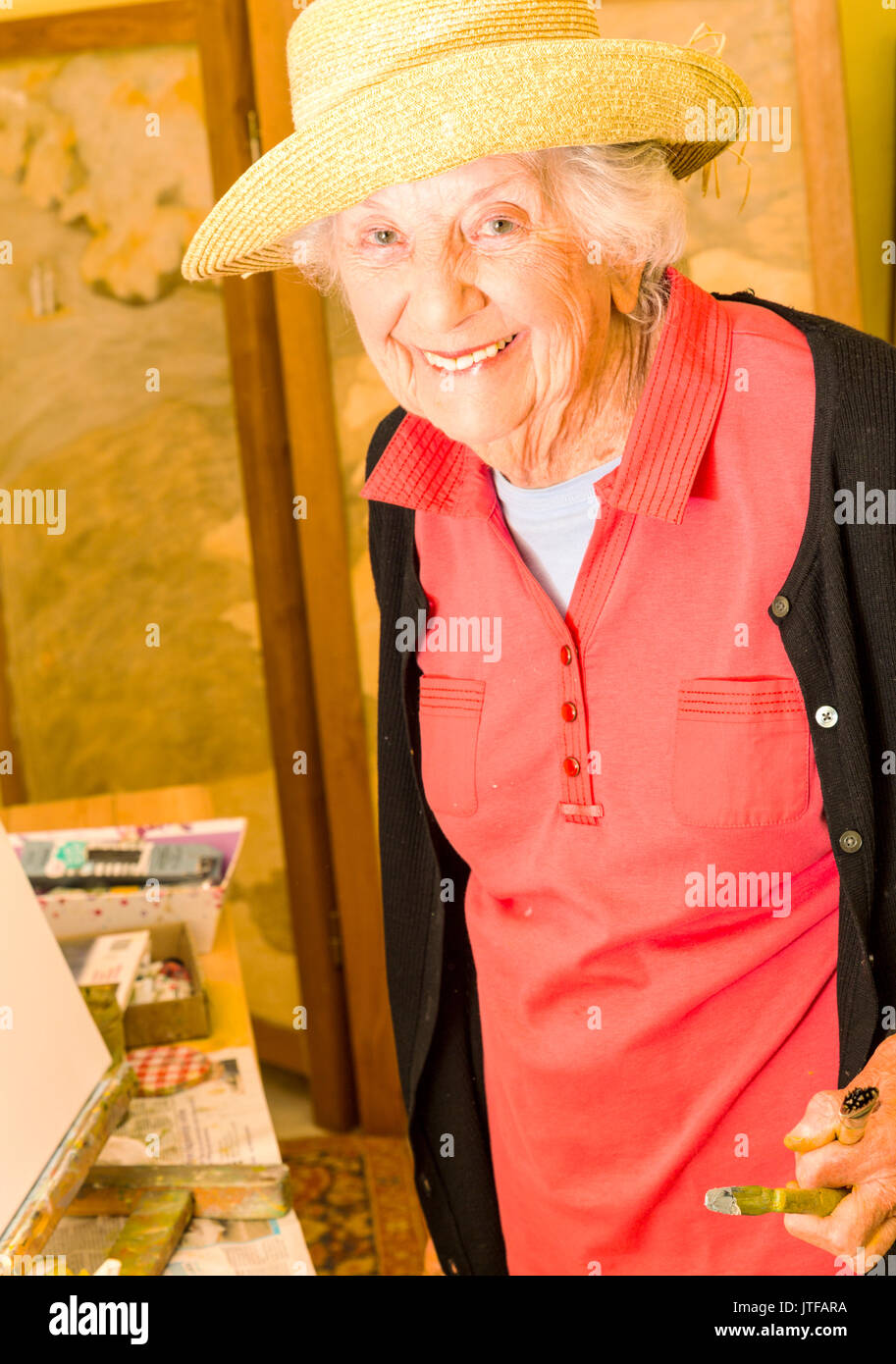 Ältere Frau Malerei an ihrer Staffelei, in ihrem Atelier in Frankreich. Stockfoto