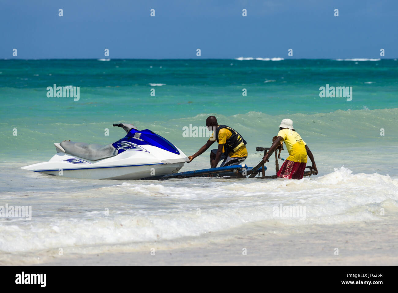 Zwei Männer drücken Jet Ski auf Trailer im Surf, Diani, Kenia Stockfoto