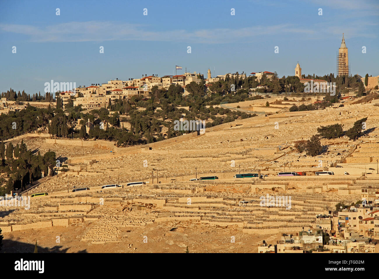 Friedhof und Häuser auf dem Ölberg in Jerusalem, Israel. Tour Busse können am Straßenrand gesehen werden. Stockfoto