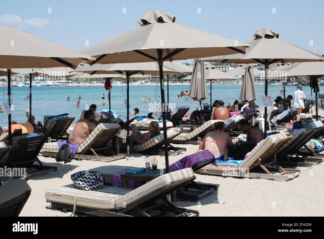 Sonnenanbeter, die drückende Hitze des zentralen Athen auf einem Strand im Süden der Stadt in Griechenland, den 8. August 2017 entgangen sind. Haushaltsordnung im Mittelmeer Land schreibt vor, dass jedes Unternehmen seinen Kunden muss mit einem Eingang für jeden Kauf bieten. Unternehmen, die gefangen sind nicht die Einnahmen kann geschlossen vor Ort für 48 Stunden. Foto: Alexia Angelopoulou/dpa Stockfoto