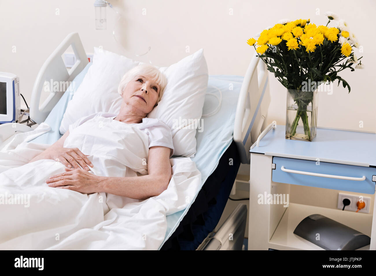 Emotionale Kranke ältere Dame, die hübsche Blumen Stockfoto