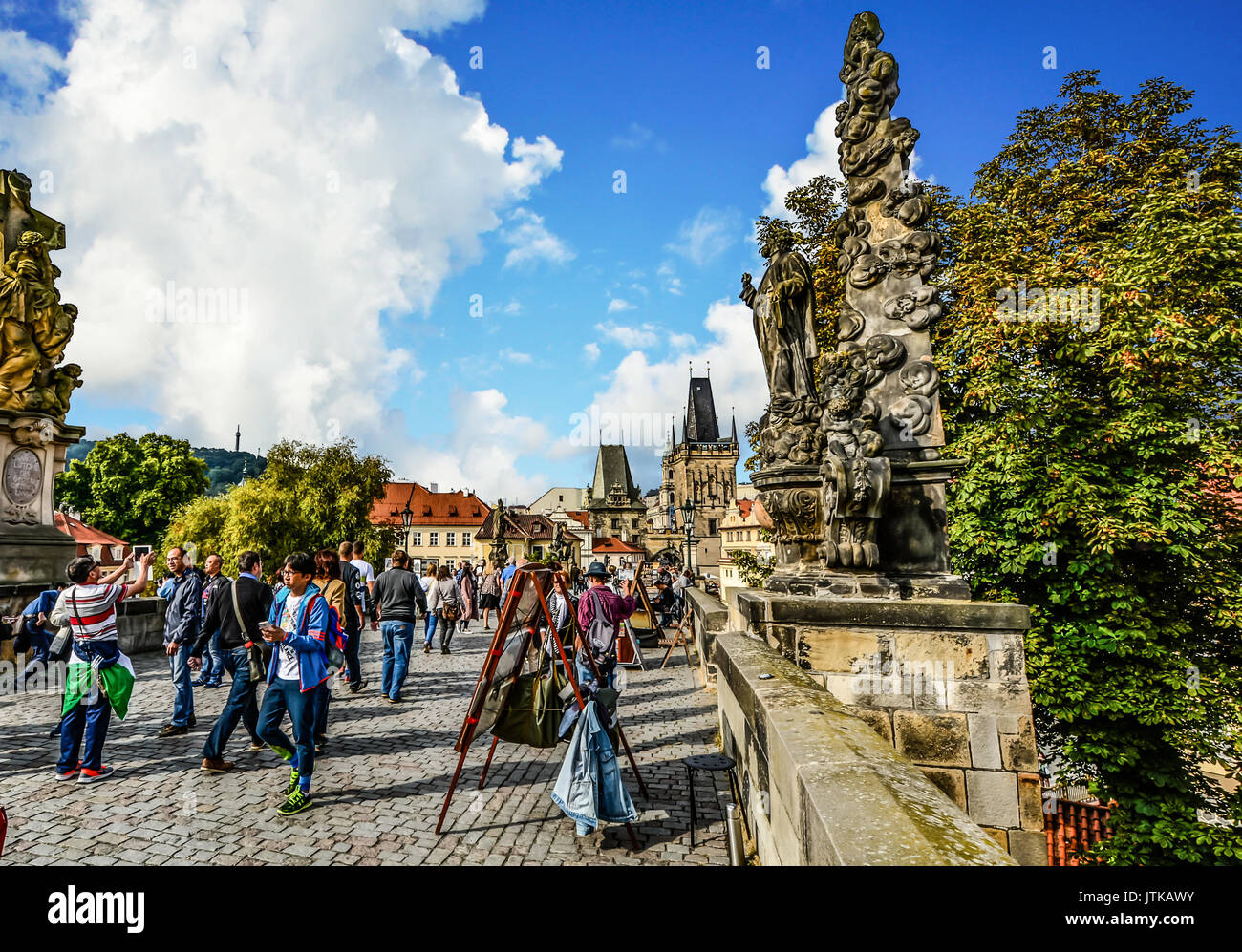 Über die Karlsbrücke in Prag als Künstler ihre Arbeit verkaufen, Touristen genießen Sie den sonnigen Tag und zwei brückentürme sind in der Ferne zu sehen Stockfoto