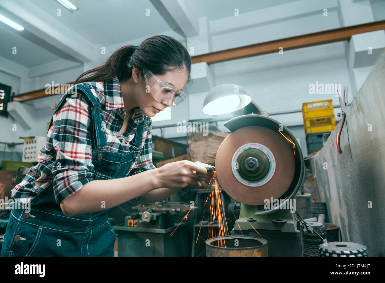 Junge schöne Fräsbearbeitung Arbeiter mit Schleifscheibe Werkzeug Schleifen von Metallteilen. Stockfoto