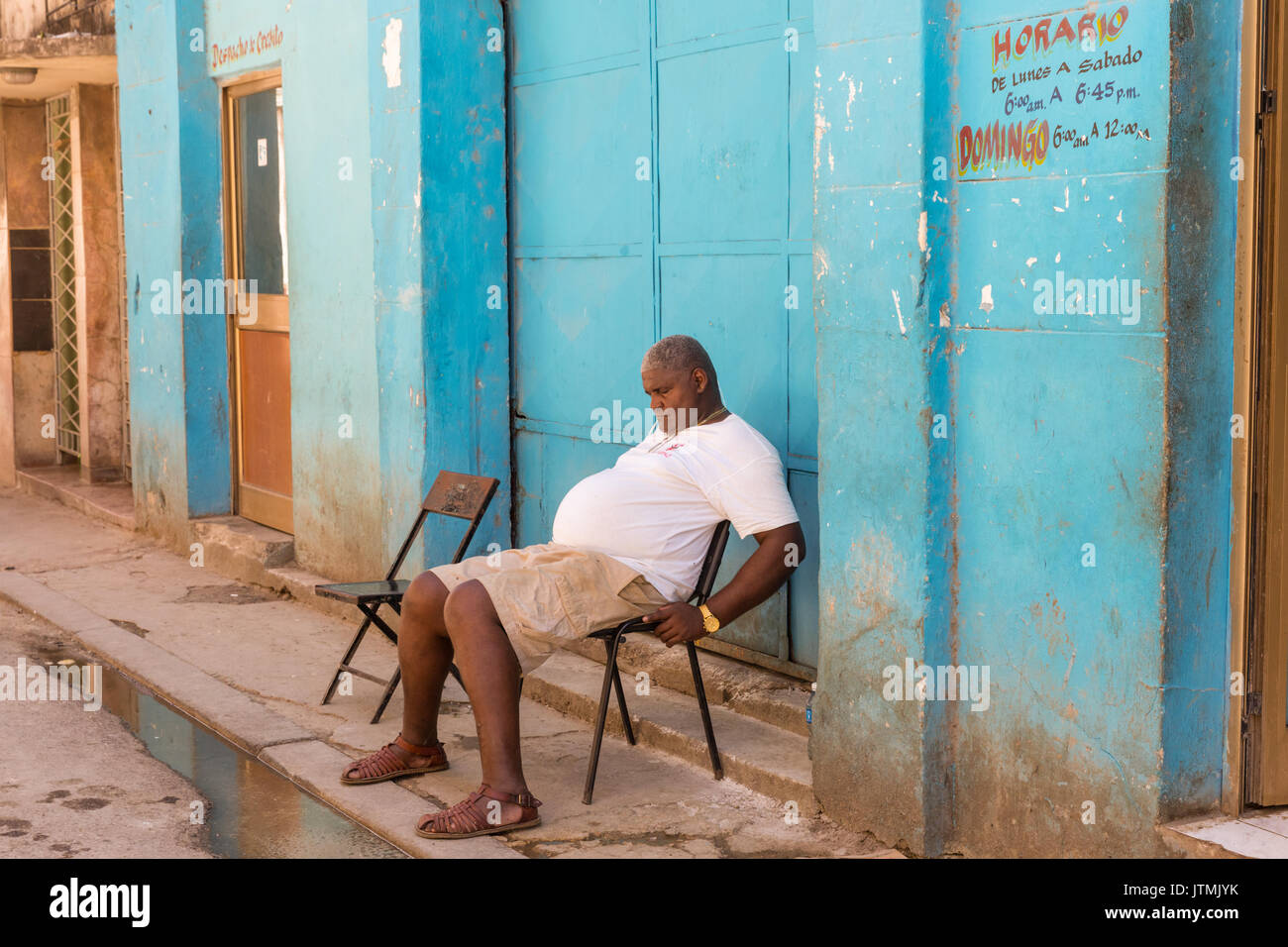Siesta, Kubanische Mann schlafend auf einem Stuhl in einer Straße in der Altstadt von Havanna, Kuba Stockfoto
