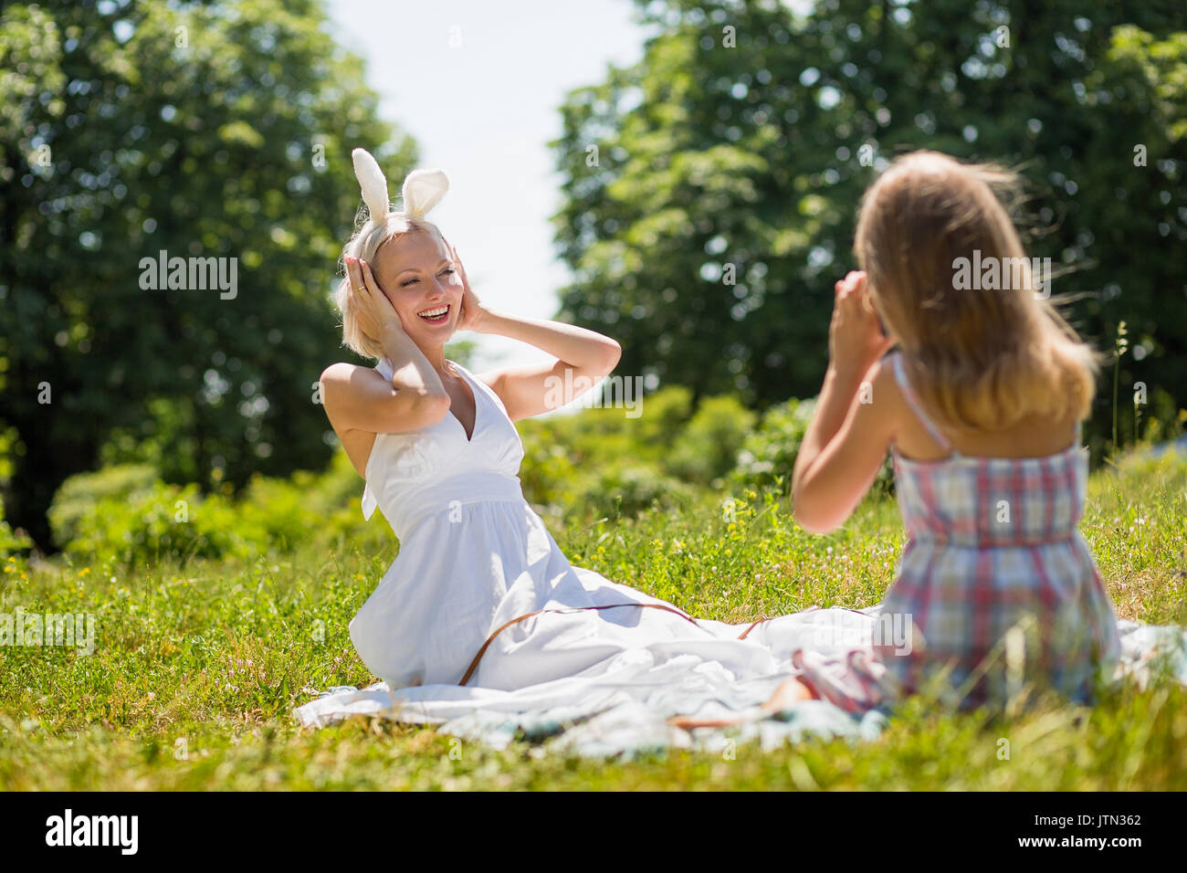 Mutter mit Hasenohren für ihre Tochter posieren. Stockfoto