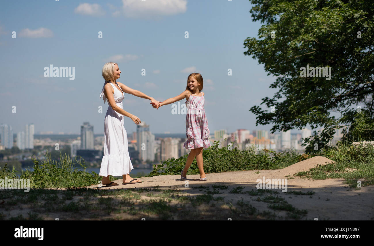 Mutter und Tochter halten sich an den Händen, Wandern im City Park. Stockfoto
