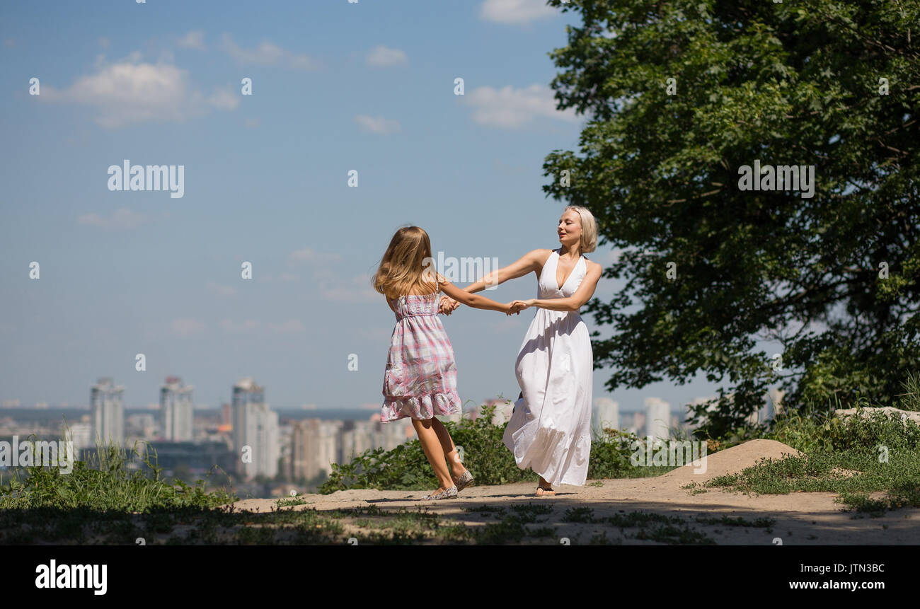 Blick auf die Stadt. junge Mutter und ihre Tochter tanzen im Park. Stockfoto