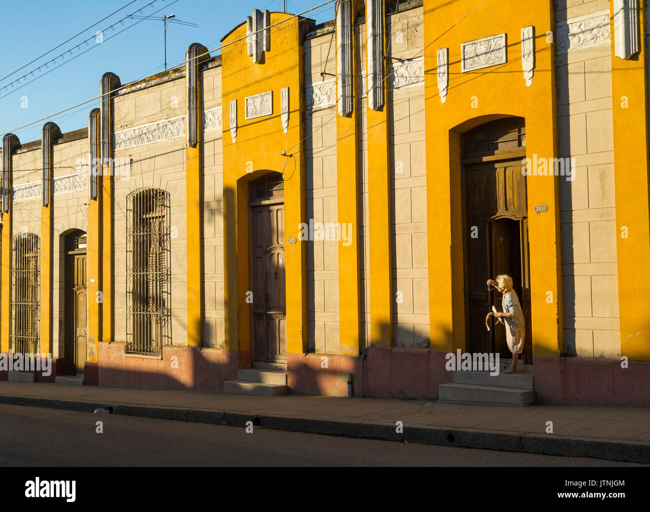 Alte Gebäude entlang Cienfuegos Straße mit einer alten Dame auf der Suche. Stockfoto