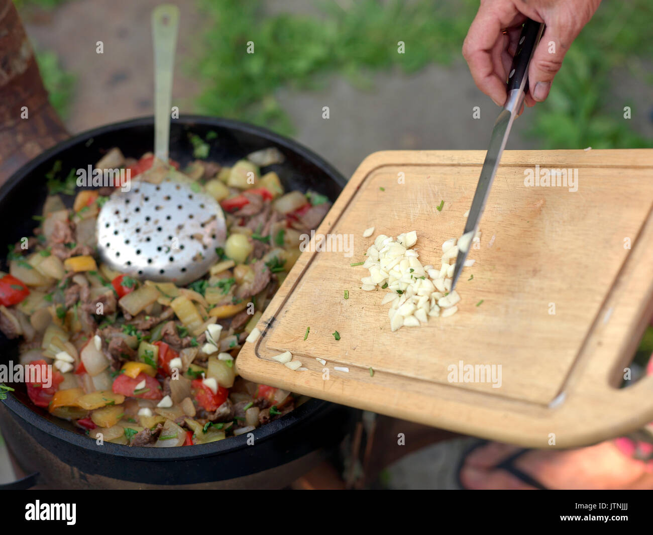 Ein Koch Seite hinzufügen gehackte Zwiebel oder Knoblauch in fast bereit, Teller, flache Tiefenschärfe closeup Stockfoto