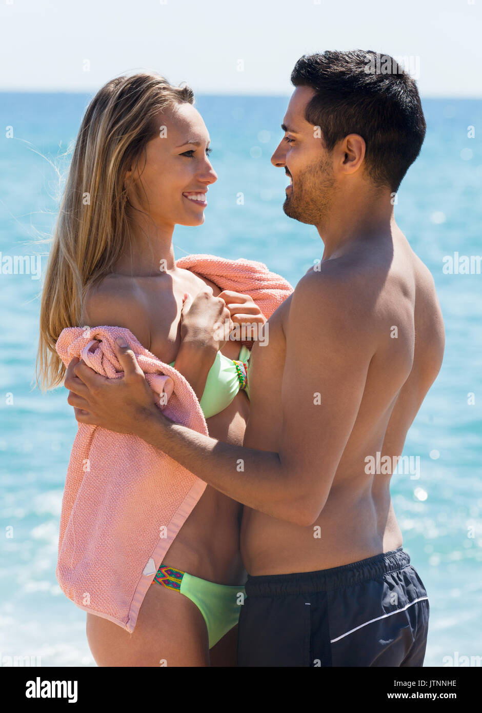 Portrait von Glückliche erwachsene Paare im Handtuch auf Sandstrand gewickelt Stockfoto