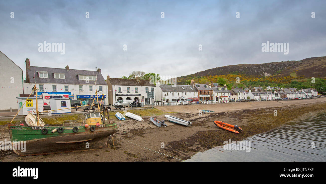 Panoramische Ansicht des Schottischen Küstenstadt Ullapool mit weiß gestrichenen Geschäfte und Häuser und Boote im Hafen neben Main Street Stockfoto