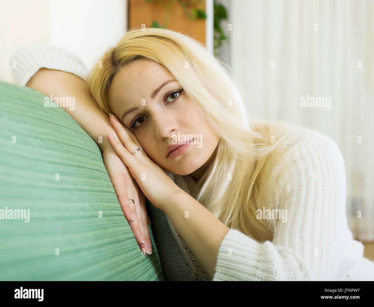 Weinend blonde Frau auf dem Sofa Stockfoto