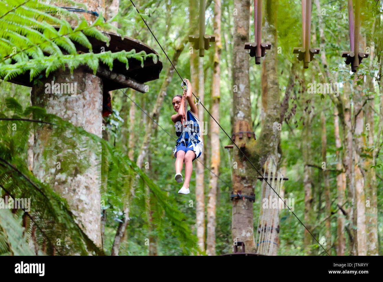 Ein Mädchen fährt eine Seilrutsche in einem Treetop Adventure Park, Bali, Indonesien Stockfoto