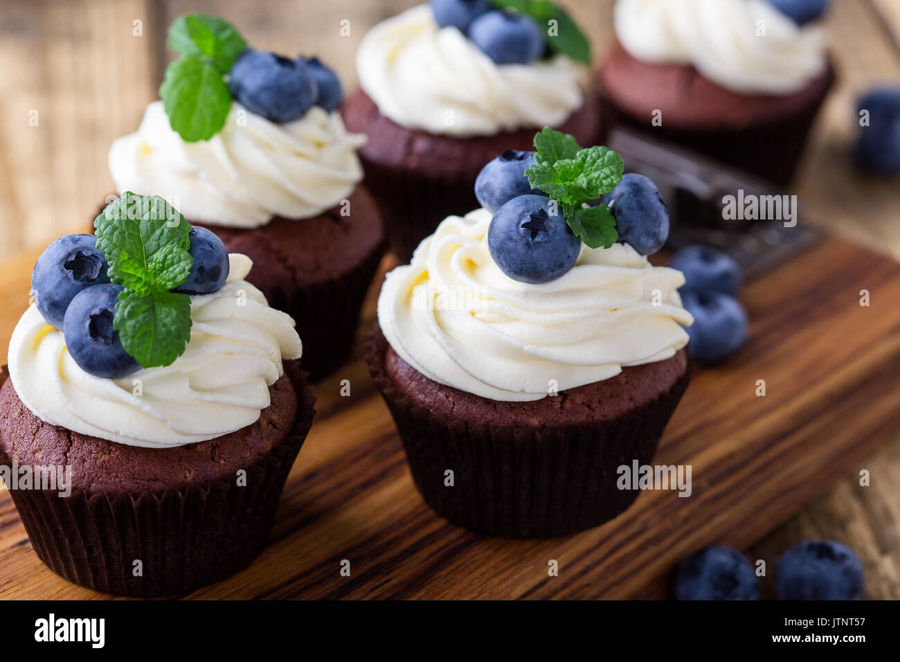 Blueberry und Rahm Käse Schokolade Cupcakes auf Holzbrett. Hausgemachte Sommer Dessert auf rustikalen Tisch Stockfoto