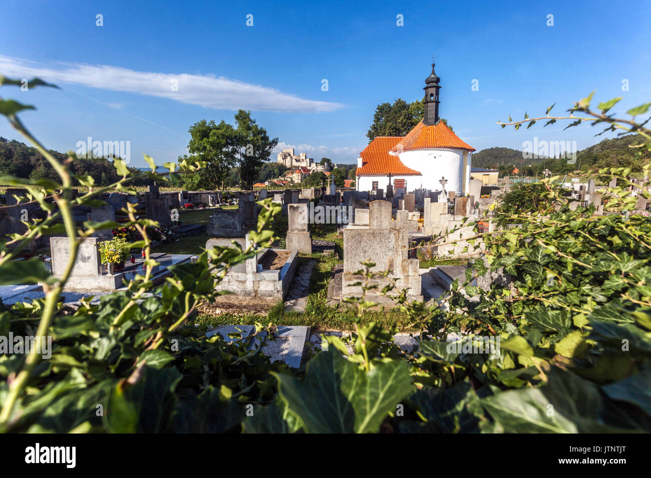 Ländlicher Friedhof mit einer kleinen Kirche, im Hintergrund Schloss Rabi, Tschechische Republik Stockfoto