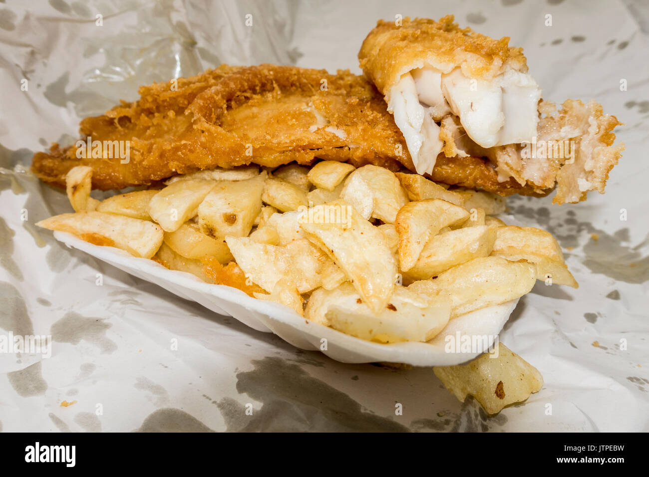 Traditionelle britische fast food Takeaway Mahlzeit der zerschlagenen Fish und Chips, im Container und Papier einwickeln. Stockfoto