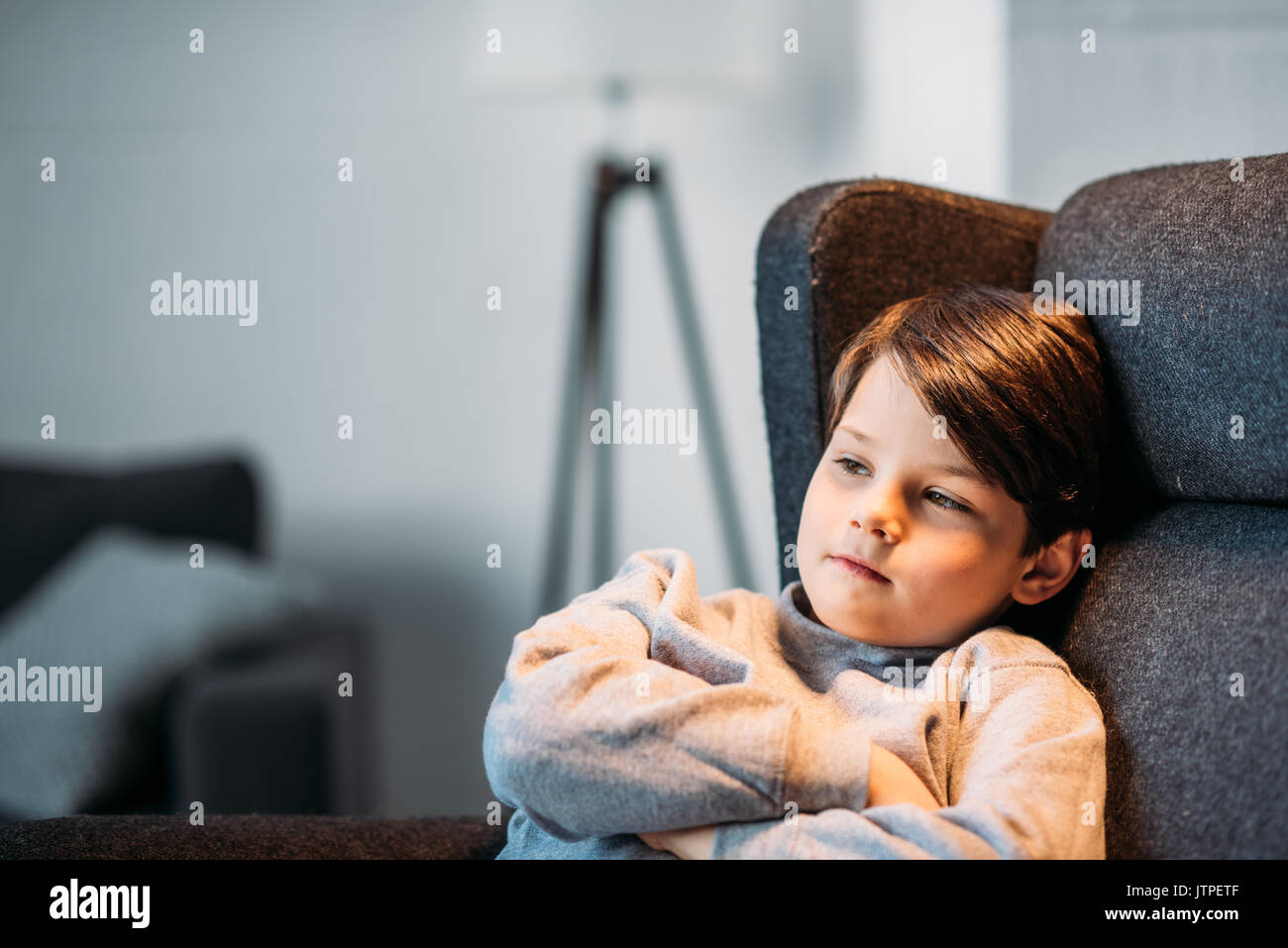 Wenig liebenswert nachdenkliche Junge im Sessel sitzt und weg zu Hause suchen Stockfoto