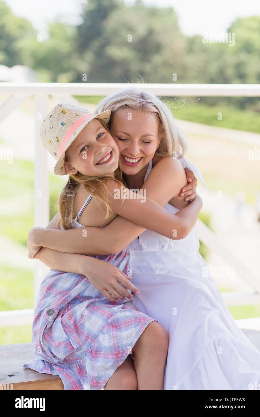 Glückliche junge Mutter ihrer kleinen Tochter umarmte. Stockfoto