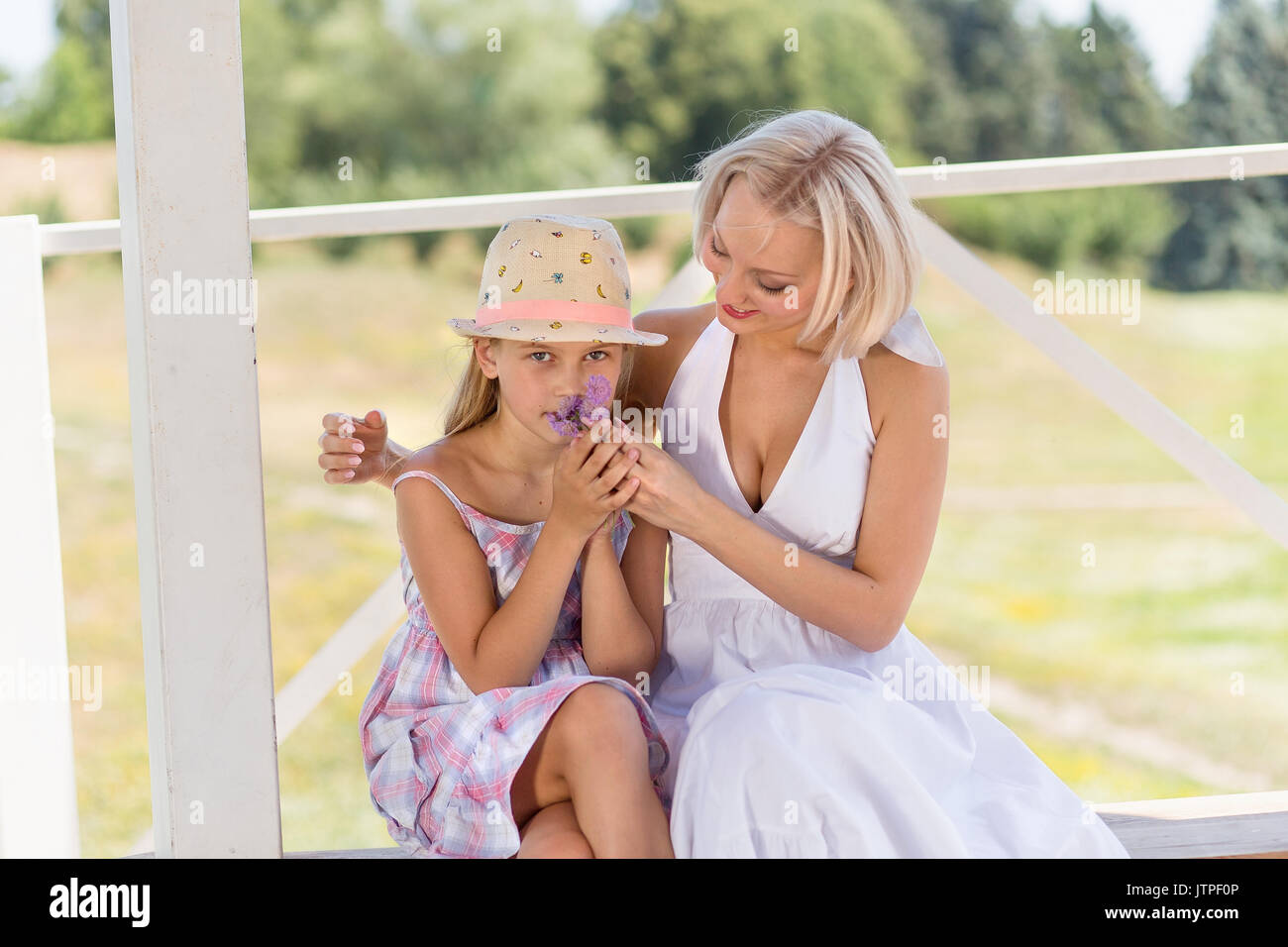Mutter mit ihrem kleinen Mädchen, Tochter sniffing eine Blume. Stockfoto