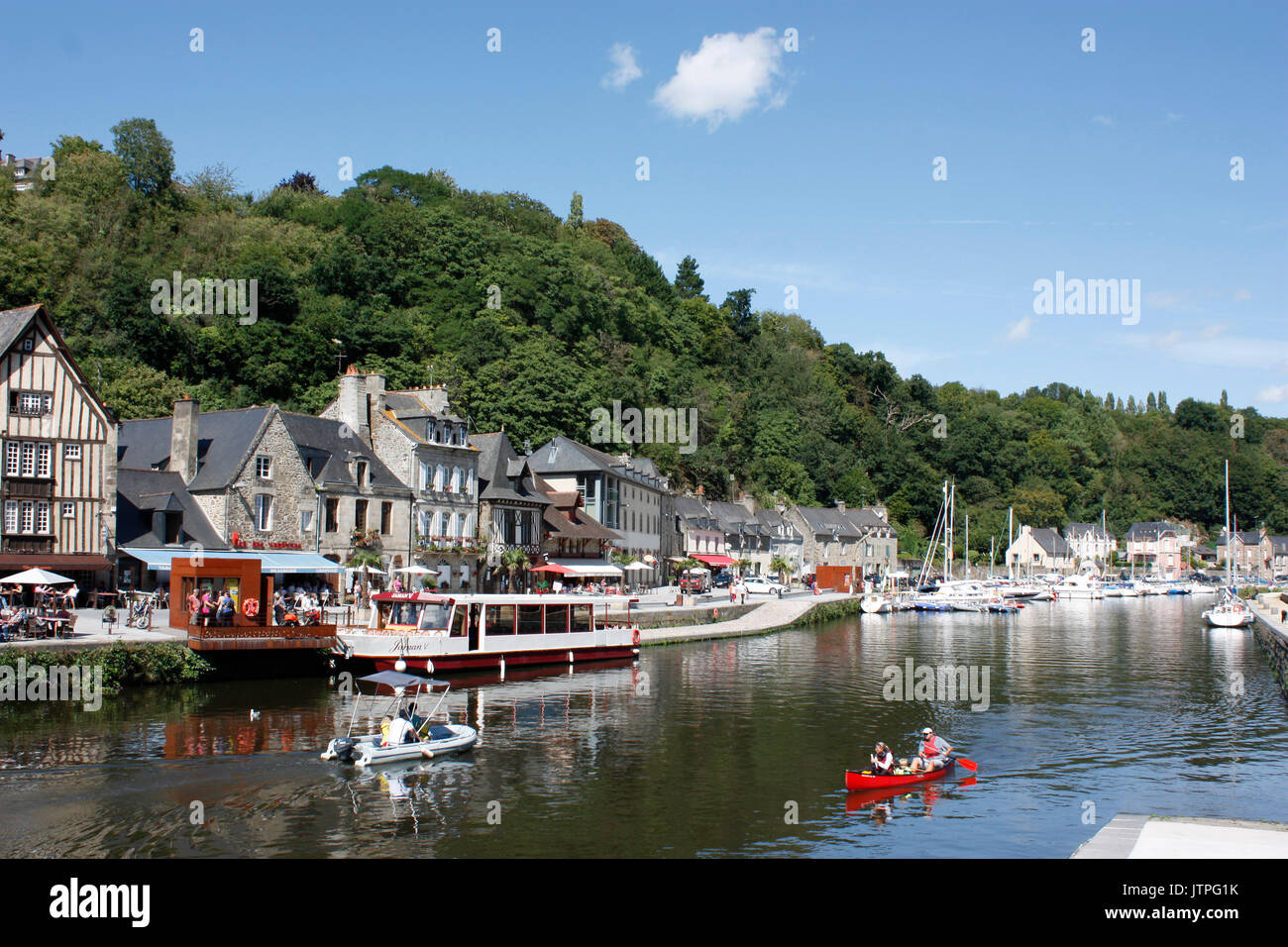 Frankreich. Der Bretagne. Dinan. Harbourside Häuser und Restaurants am Fluss Rance mit Touristen im Kanu und Motorboot. Stockfoto