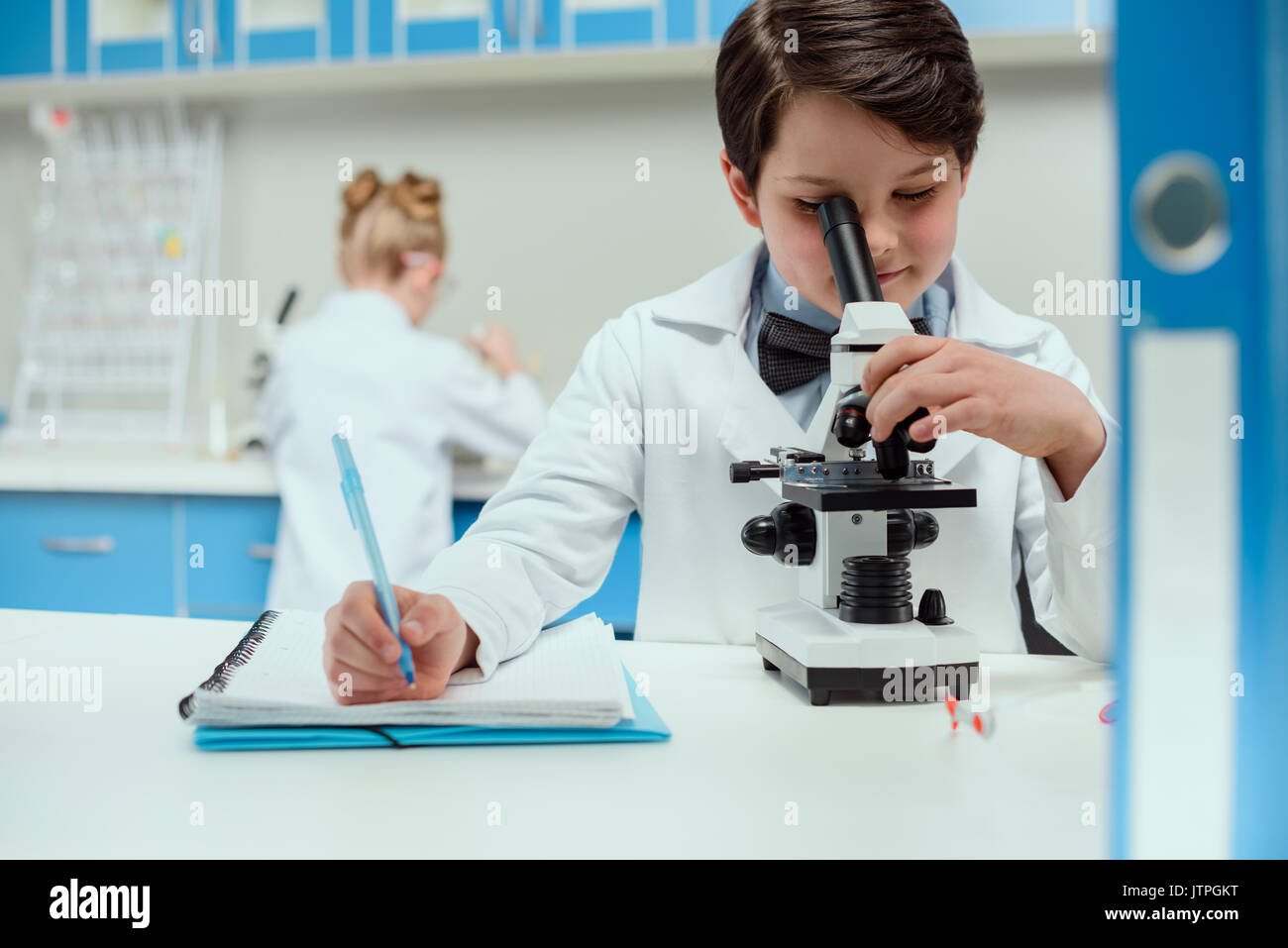 Schüler mit Mikroskop und Copybook in Science Laboratory, Science Lab für Kinder Konzept Stockfoto