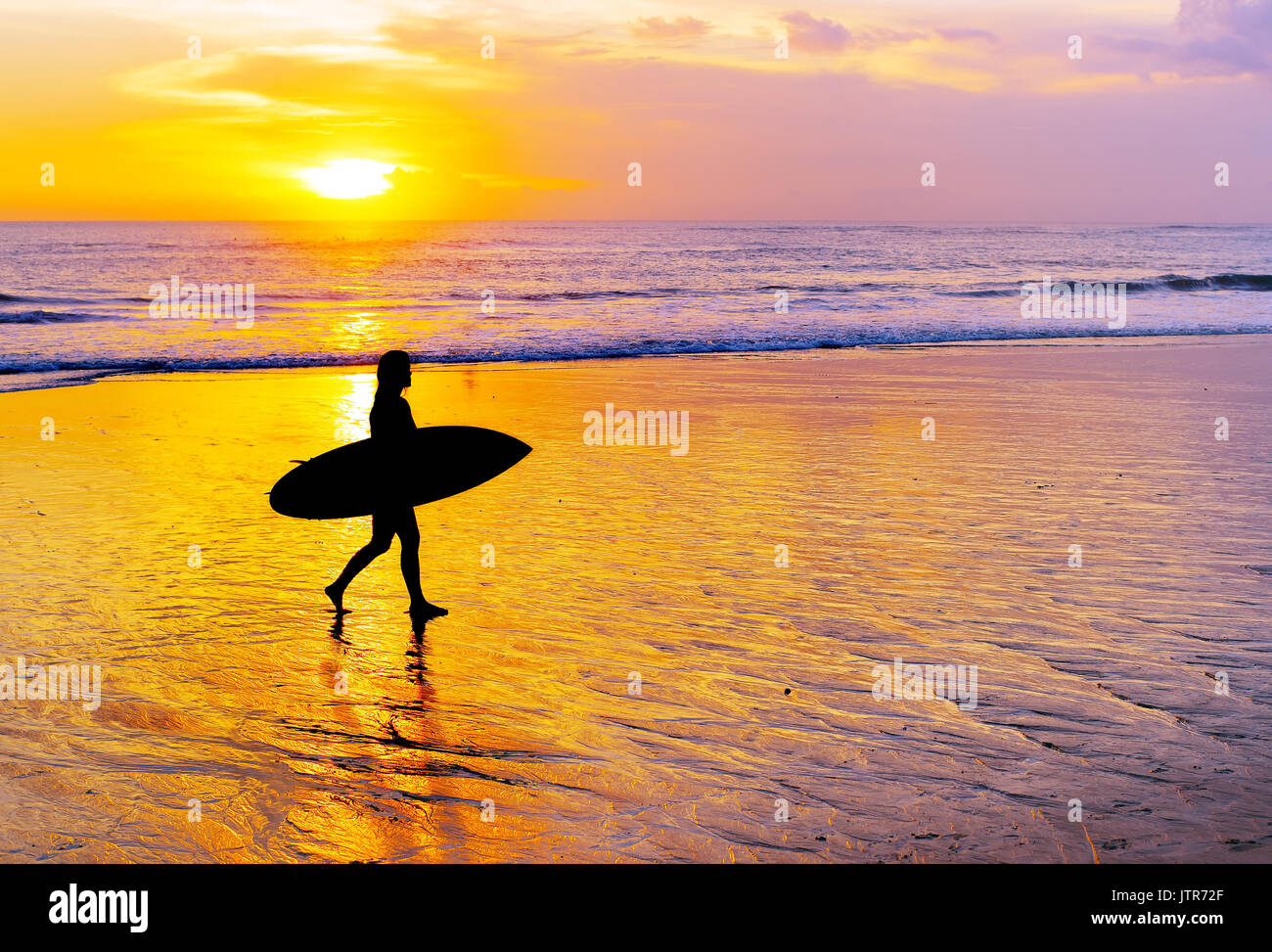 Frau Surfer zu Fuß am Strand mit Surfbrett bei Sonnenuntergang. Die Insel Bali Stockfoto