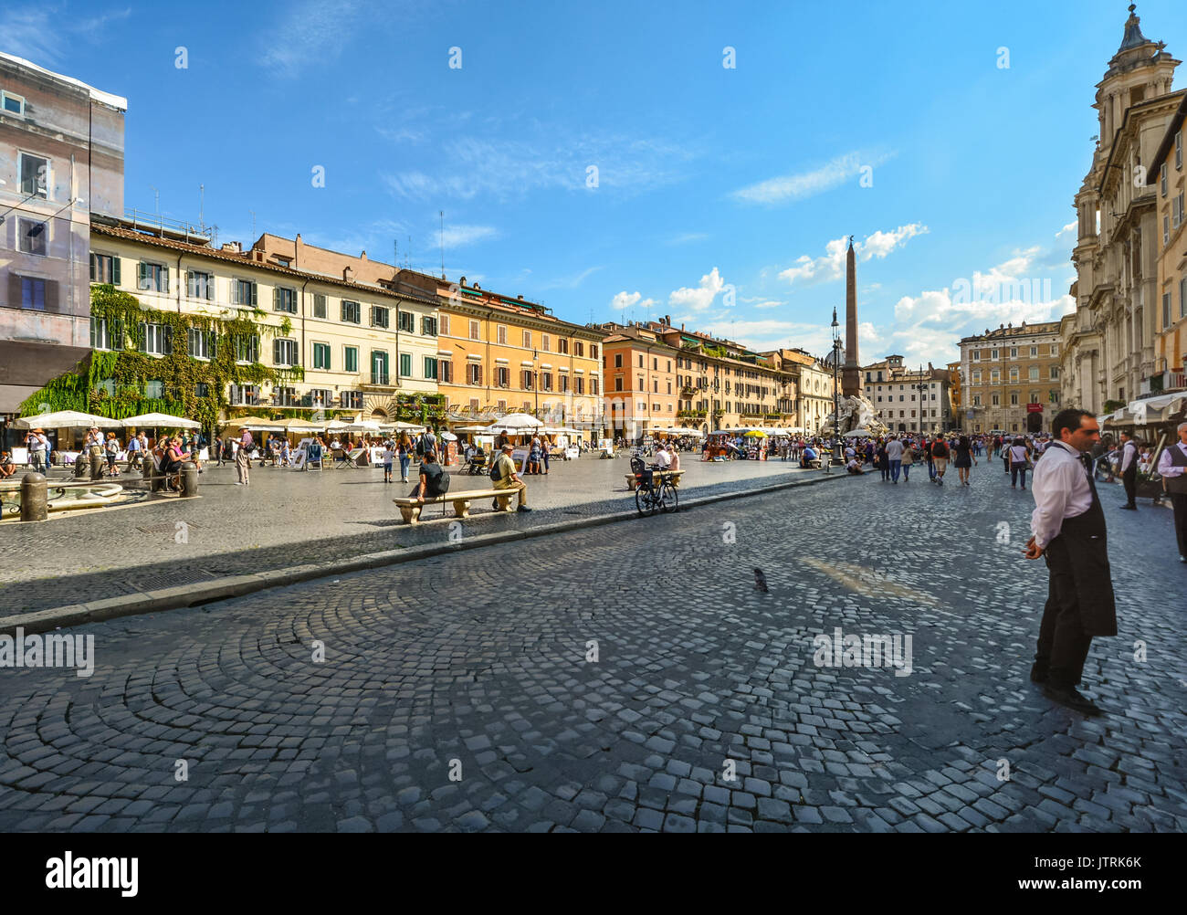 Ein Maitre d oder Oberkellner steht vor einem Café oder Restaurant in der Piazza Navona in Rom Italien an einem sonnigen Tag mit Touristen Stockfoto