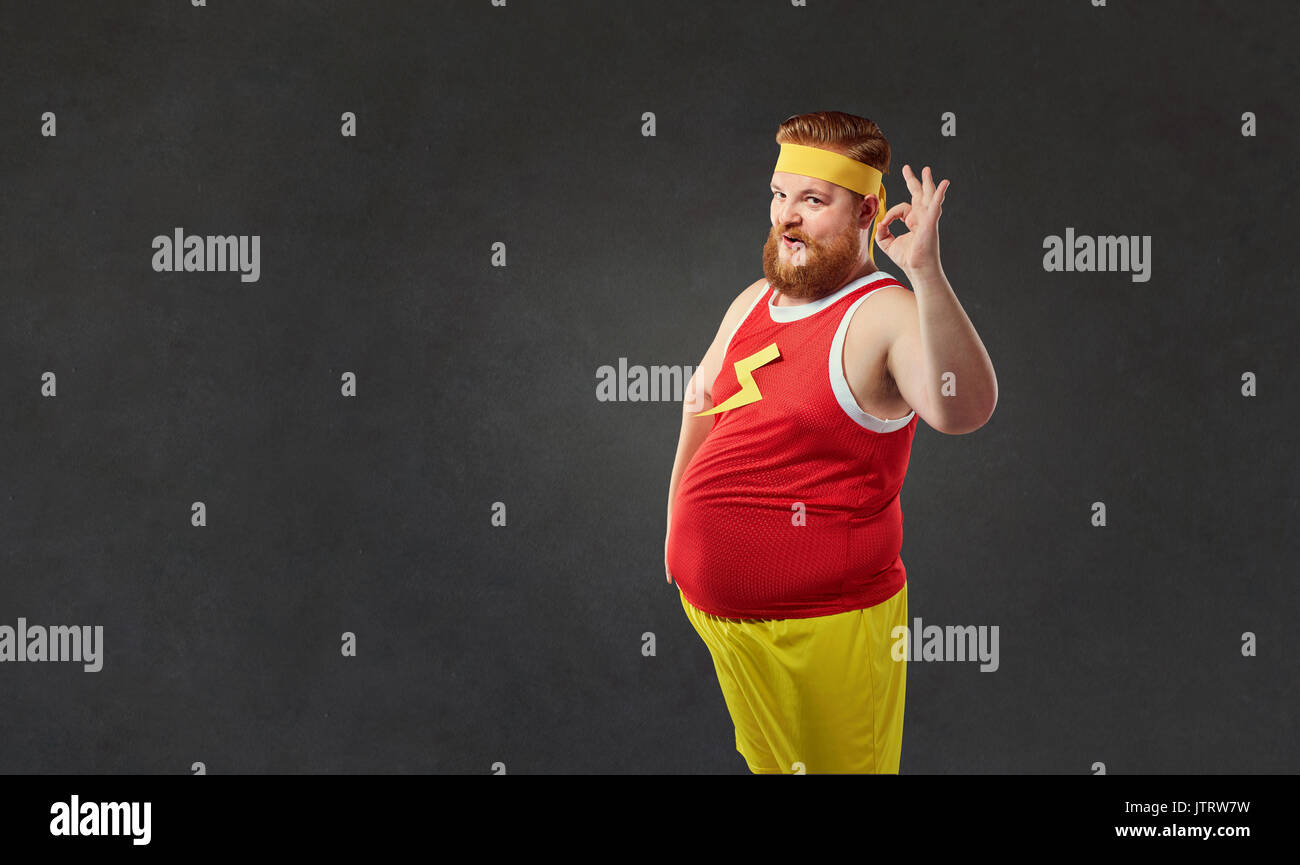 Funny fat man im Sport Kleidung zeigt seine Hand in Ordnung. Stockfoto